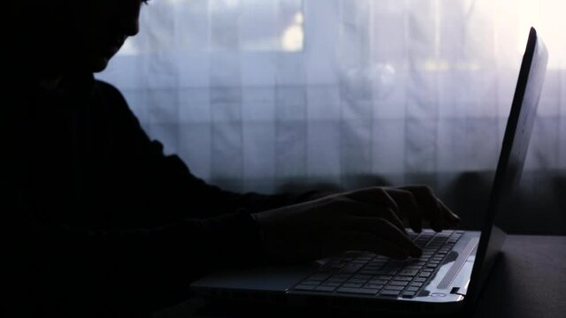 A man who opens the laptop and then works on it. Write a message. Dark image, counterpoint. Haker