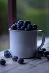 Blueberries in vintage tin cup on rustic wood background