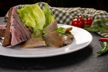 Traditional Russian snacks. A set of pickled vegetables and mushrooms with lettuce leaves on a white plate. Dark background