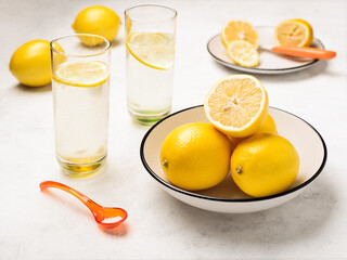 Lemons in a bowl and glasses of lemon juice drinks