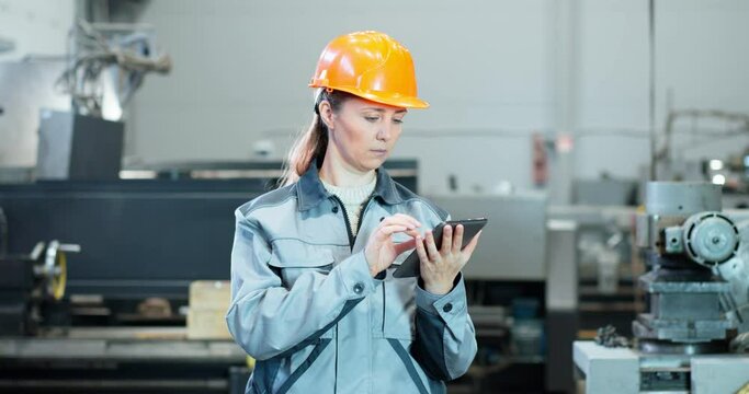 women industrialists browses information using laptop. She works in a heavy industry manufacturing facility.
