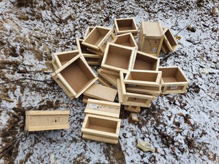 Open wooden mailboxes are heaped outside in the snow.