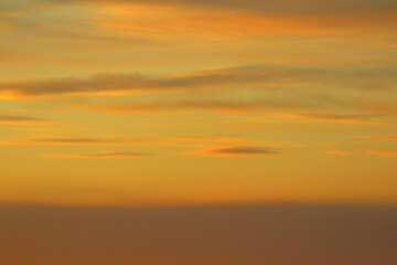Sun below the horizon and clouds in the fiery dramatic orange sky at sunset or dawn backlit by the...