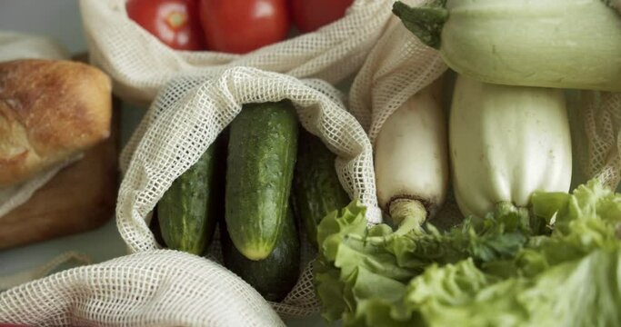 Vegetables, fruits in reusable eco cotton bags on table. Zero waste shopping concept. Plastic free items. Multi-use, reuse, recycle. Eco friendly canvas grocery bag with tomatoes, pepper, bread.