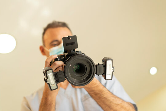 Low angle view of dentist doctor holding a professional photo camera with ring flash