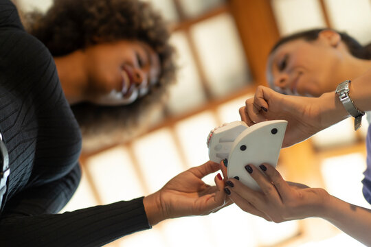Low angle view of cheerful African American lady talking with Caucasian female dentist about teeth implants in dental clinic