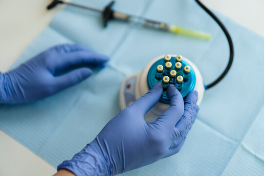 Hands of anonymous dentist in latex gloves putting vial with anesthesia into syringe over table in clinic