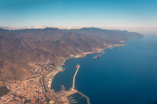 Aerial view of part of modern aircraft flying over amazing mountainous and coastal port landscape in morning in Tenerife