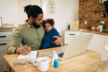 Caring black father taking care of his ill small daughter while working at home.