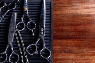 From above of vintage kit of various hair cut scissors and clamp arranged on black board on shabby wooden table