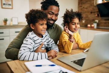 Happy black father and children having video call over laptop at home.