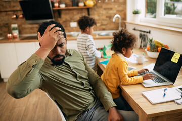 Working African American father feeling frustrated while working at home.