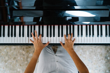 Top view of crop anonymous female musician playing piano while practicing at home at weekend
