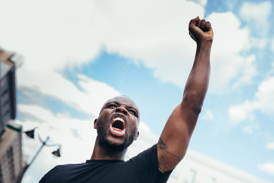 Man protesting at a rally for racial equality raising arms. Black Lives Matter.