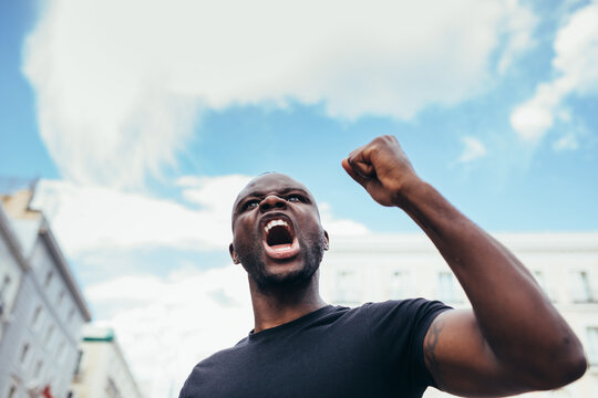 Man protesting at a rally for racial equality raising arms. Black Lives Matter.