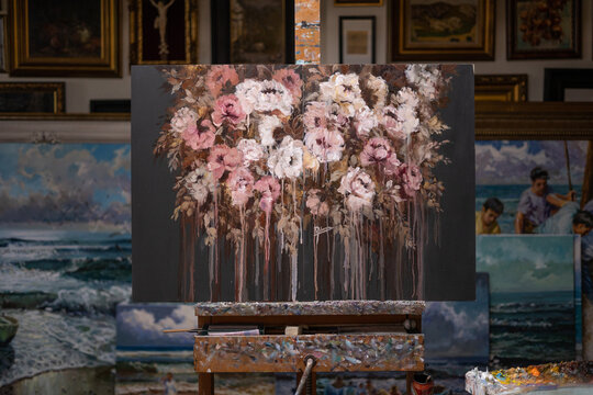 Beautiful floral painting on canvas placed on easel at workplace in creative art workshop