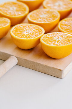 Closeup of halves of ripe juicy oranges on wooden chopping board in studio on white background