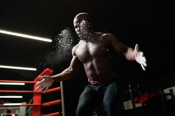 Muscular african american weightlifter preparing for barbell training in the gym. Claps hands and...