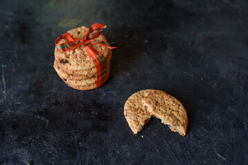 Shortbread cookies with pieces of chocolate are tied with red beautiful ribbon on a dark background. A place for text. View from above.