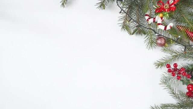 Fir branches with Christmas decorations and a garland on a white background.