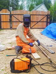 Craftsman, welds a metal pipe on the suburban area