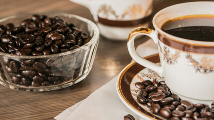 Cup of coffee and coffee beans on white paper on old wooden background