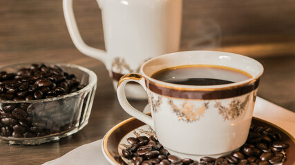 Cup of coffee and coffee beans on white paper on old wooden background