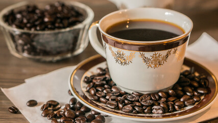 Cup of coffee and coffee beans on white paper on old wooden background