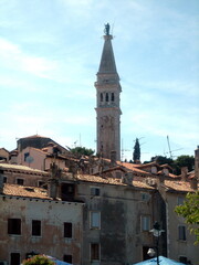 Fototapeta premium The tall tower of the city hall rises above the tiled roofs of houses in an ancient European city.