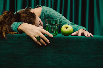 Woman lying on table with cocktail drink and green apple