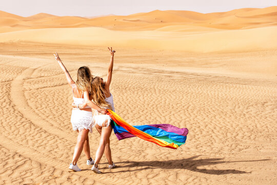 Mid adult women with gesturing peace sign while walking with flag at dessert