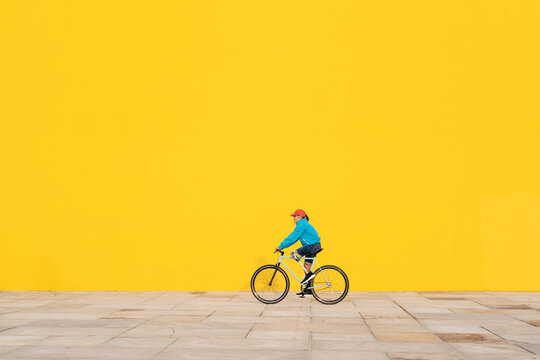 Disabled man riding bicycle against yellow wall