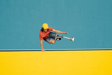 Disabled athlete doing handstand against multi colored wall