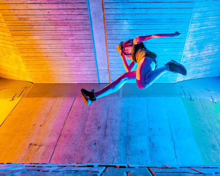 Young woman with hat dancing against wall