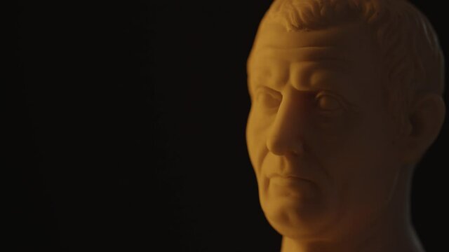 Marble bust statue of Roman Emperor Julius Caesar on a black background