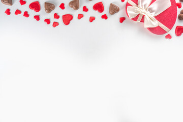 Red hearts, gift with ribbon and chocolates hearts flat lay, Valentine day and love background. Valentine's hearts ornament on white backdrop copy space top view