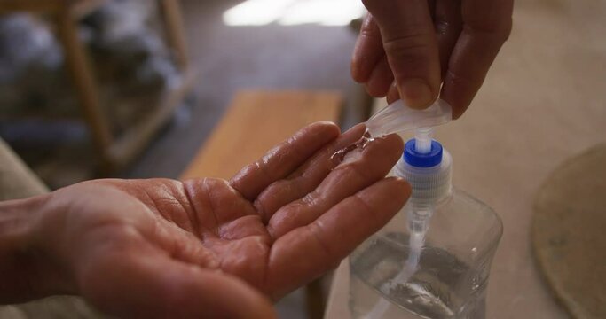 Close up view of potter using hand sanitizer at pottery studio