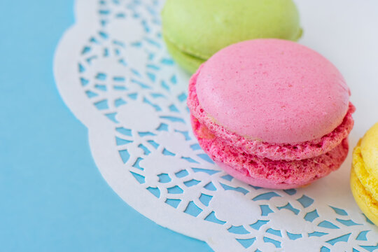 Sweet delicious french round almond biscuits.Colorful almond macarons on white napkin on blue background. French pastry