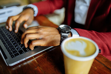 african american man getting online education and drinks coffee to go frop paper eco cup
