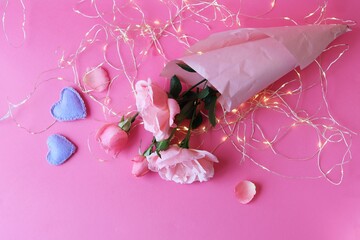 Fresh roses on a pink background, hearts, illumination, concept of romantic congratulations on Valentine's Day, happy birthday cards, wedding invitation