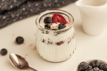 Healthy breakfast in a glass jar: homemade yogurt, berries, whole grain cereal. Healthy nutrition concept. Closeup. Horizontal