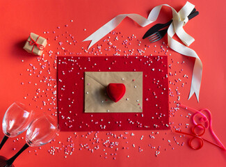 envelope, red heart-shaped box, wine glasses, gift, fork and knife tied with a light ribbon on a red background, top view, Valentine's day, romantic card