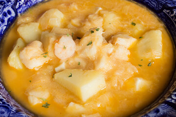 Close-up of cooked cod with prawns, potatoes, and parsley on a decorated plate. Cooking recipes with fish and vegetables.