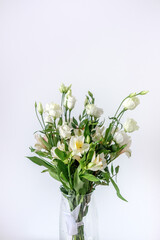 Bouquet of white alstroemerias and white eustomas in a glass vase. Beautiful flowers for women's day. A bouquet as a gift. White red green bouquet.
