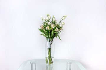 Bouquet of alstroemerias and eustomas in a glass vase on a glass table. Beautiful flowers for...
