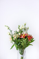 Bouquet of white and red alstroemerias and white eustomas in a glass vase. Beautiful flowers for women's day. A bouquet as a gift. White red green bouquet.
