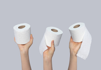 Women holding toilet paper rolls on gray background, closeup