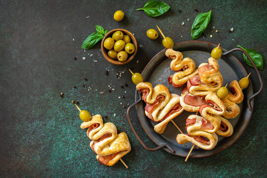 Holiday snack puff dough Christmas tree with olive and bacon on a slate or stone tabletop. Christmas and New Year background for food. Top view flat lay. Copy space.