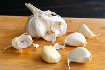 Close-up of Garlic Cloves: Peeling and smashing garlic cloves on a bamboo cutting board