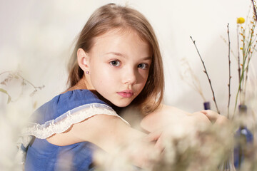 Portrait of a girl in blue dress sitting among dry twigs